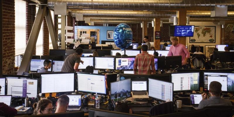 Busy open-plan tech office with rows of staff at dual monitors and a blue Flexport balloon floating overhead