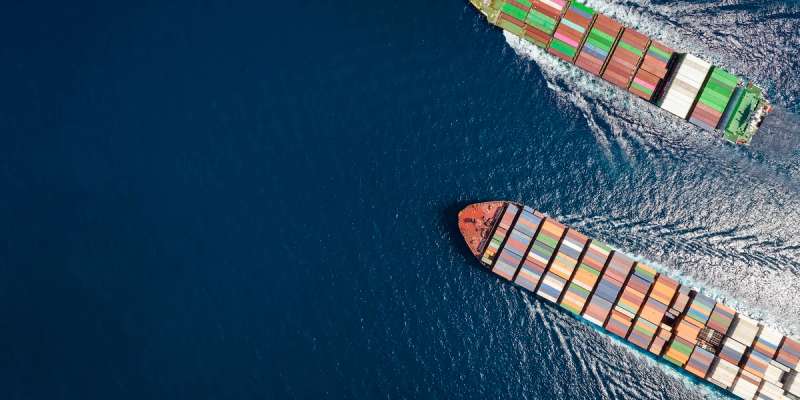 Aerial view of two container ships passing in opposite directions on dark blue water