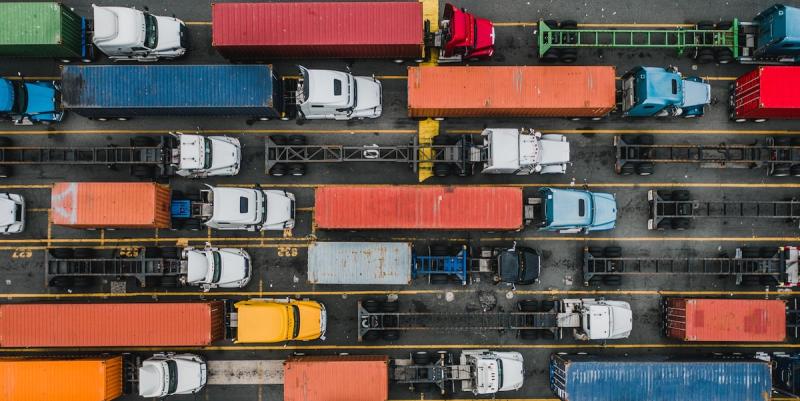 Aerial view of rows of cargo trucks with colorful shipping containers parked in a yard