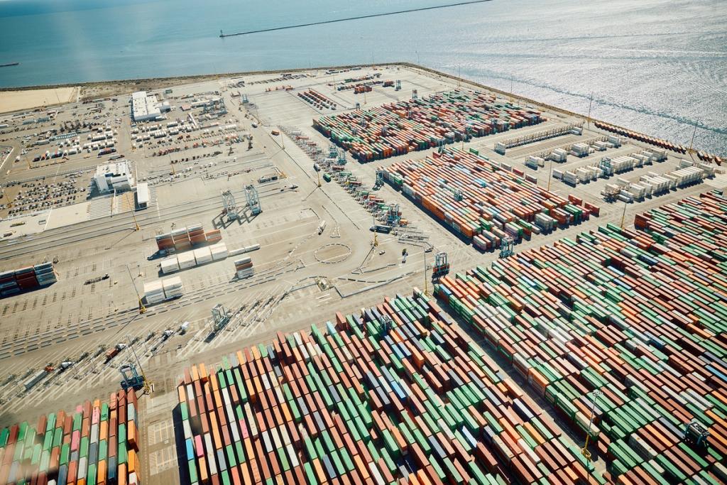 Aerial view of a port terminal with vast rows of stacked shipping containers by the water