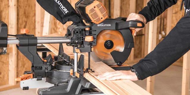 Hands using an Evolution sliding miter saw to cut lumber on a construction site
