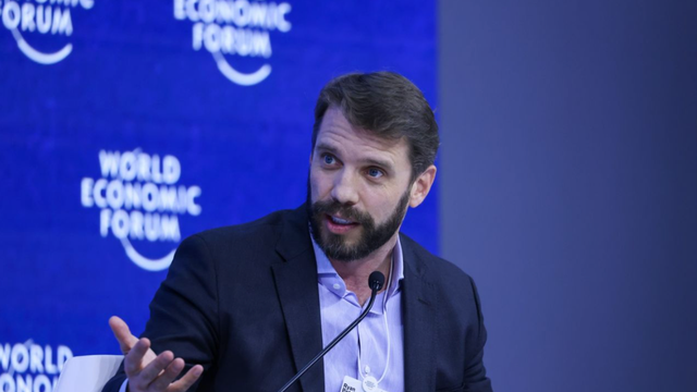 Bearded man speaking on a panel in front of World Economic Forum branding