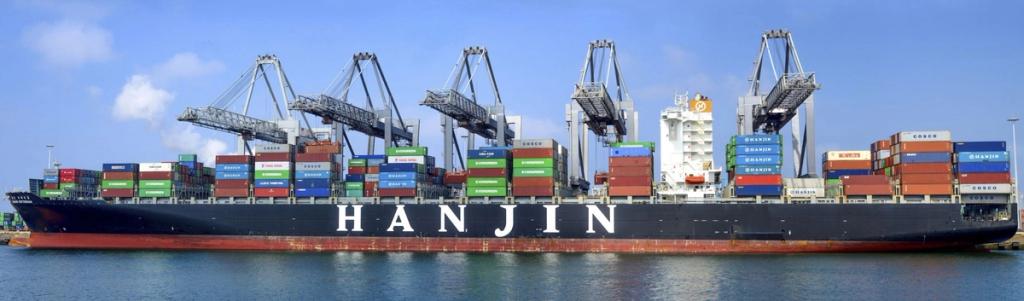 Container ship marked HANJIN docked under gantry cranes, loaded with stacked shipping containers