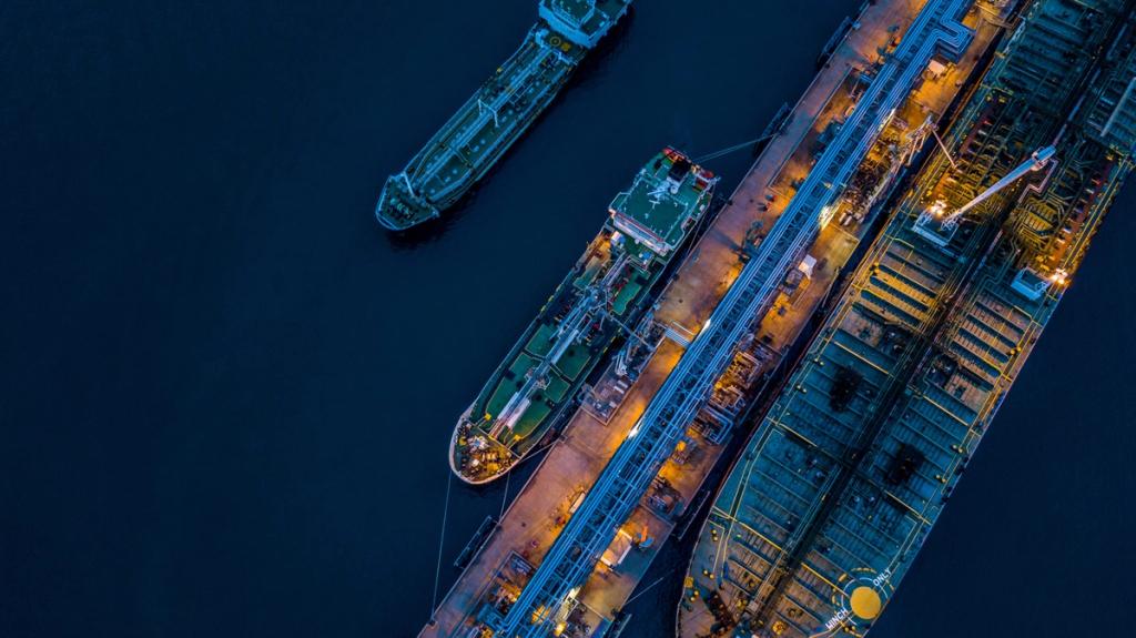 Aerial night view of tanker ships moored alongside an illuminated industrial port terminal