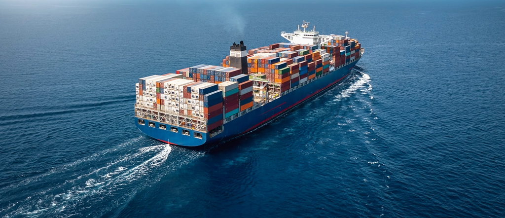 Large cargo ship transporting stacked shipping containers across the open ocean.