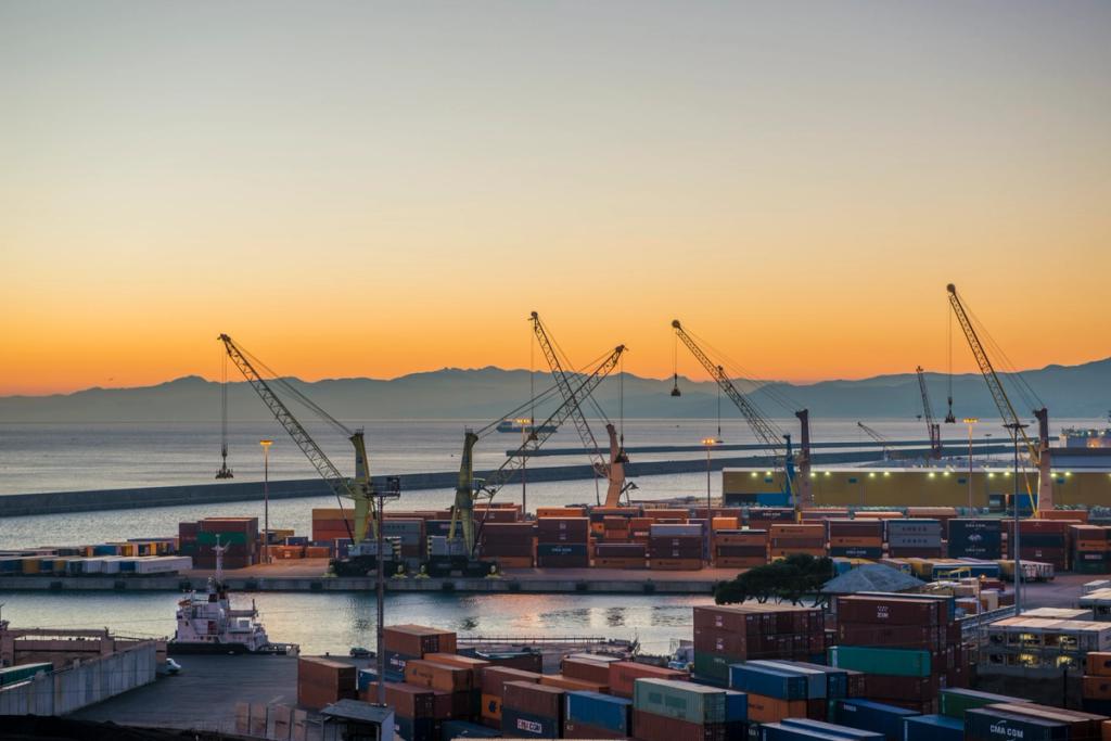 Container terminal at dusk with quay cranes and stacked containers along the waterfront, orange sky