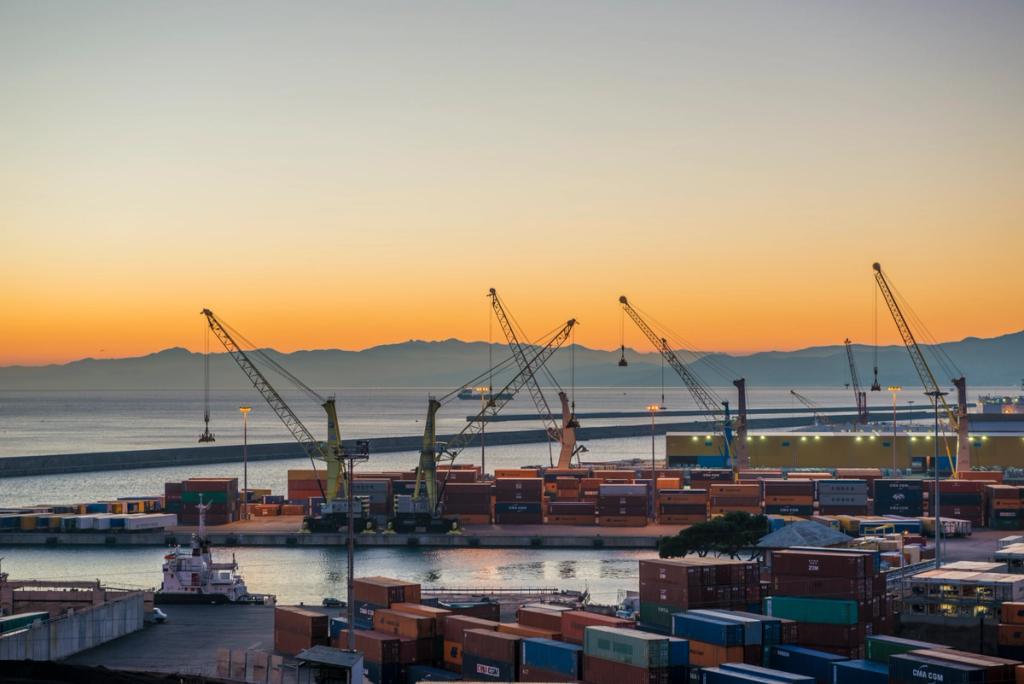Container terminal at dusk with quay cranes and stacked containers along the waterfront, orange sky