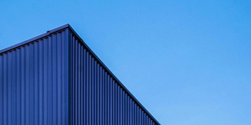 Upward view of a corrugated metal warehouse roofline against a clear blue sky
