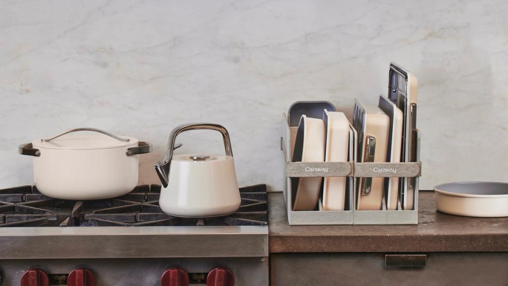 Cream Caraway pot and kettle on a stovetop beside a bakeware storage rack