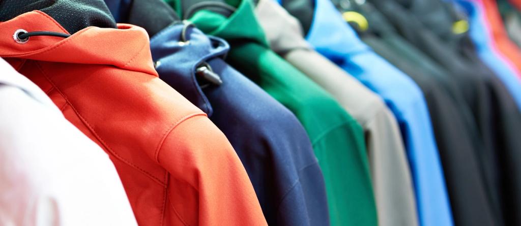 Close-up of a row of outdoor jackets in orange, navy, green and blue hanging on a rack