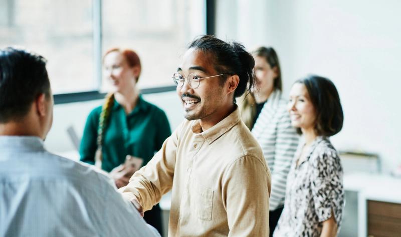Smiling colleagues greeting and shaking hands in a bright office