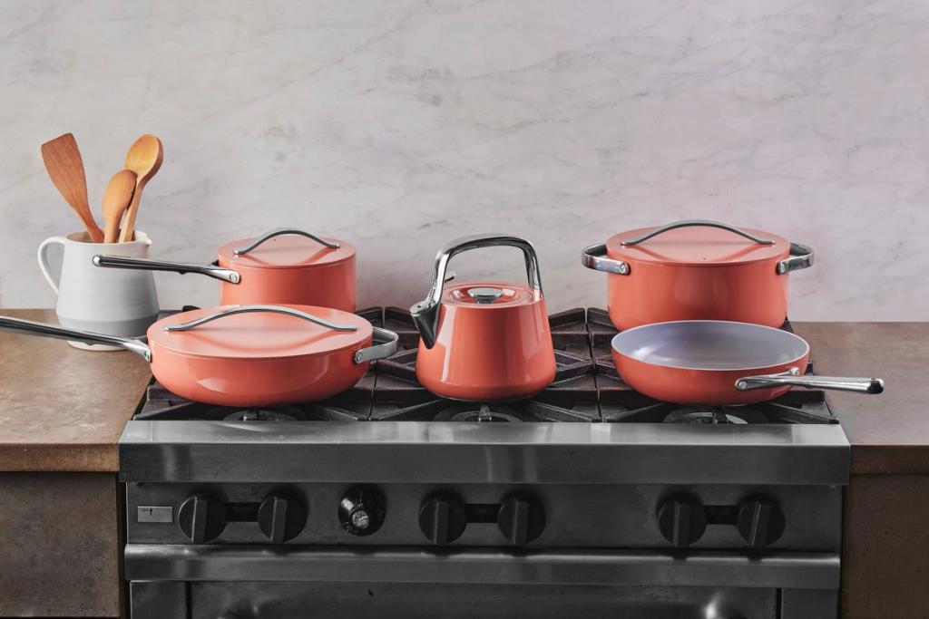 Terracotta-colored Caraway pots, pans, and kettle on a gas stovetop