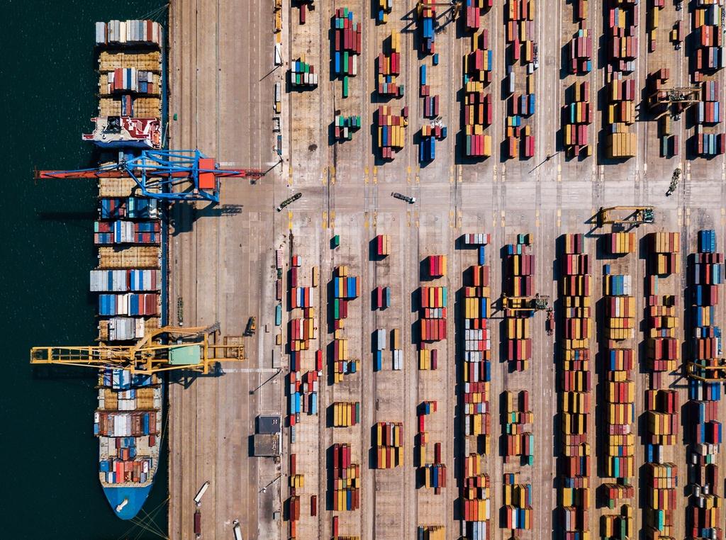 Aerial view of a shipping port with cargo containers being unloaded by container handling equipment.