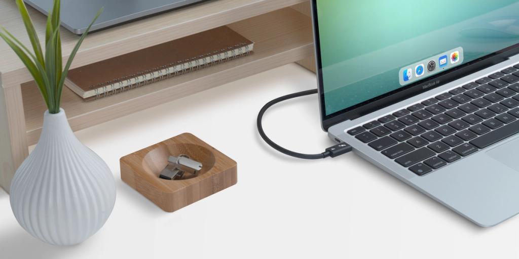 Plugable USB adapter and reversible cable on a wooden desk beside a MacBook Air