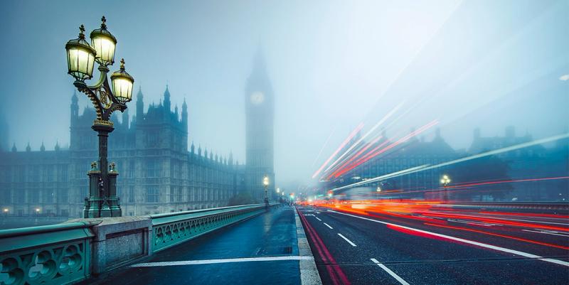 Foggy dusk on Westminster Bridge with an ornate lamp post, Big Ben silhouette and red traffic light trails.