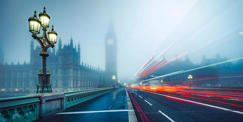 Foggy dusk on Westminster Bridge with an ornate lamp post, Big Ben silhouette and red traffic light trails.