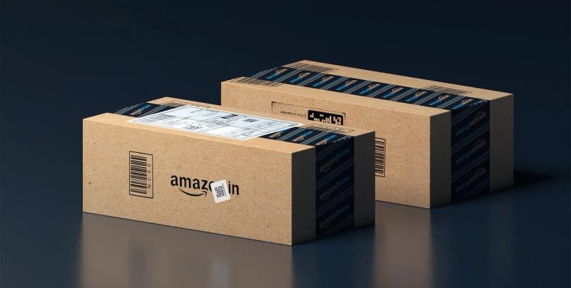 Two kraft cardboard boxes sealed with Amazon Prime tape and an Amazon.in shipping label on a dark surface