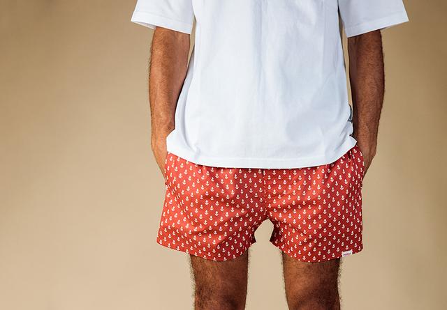 Man in white tee and red anchor-print Pockies boxer shorts photographed from behind