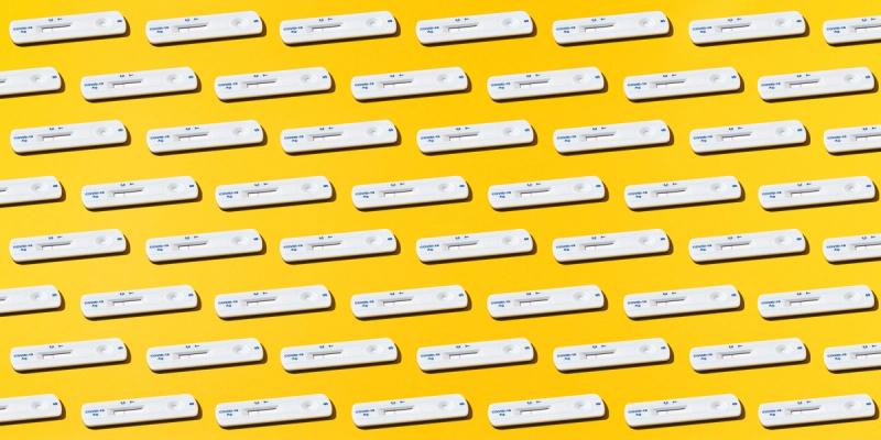 Repeating grid of white COVID-19 antigen rapid test cassettes on a bright yellow background