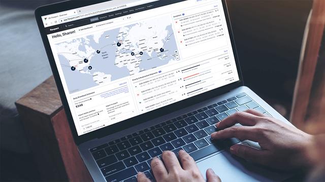 Hands typing on a laptop showing the Flexport platform dashboard with a world map and shipment data