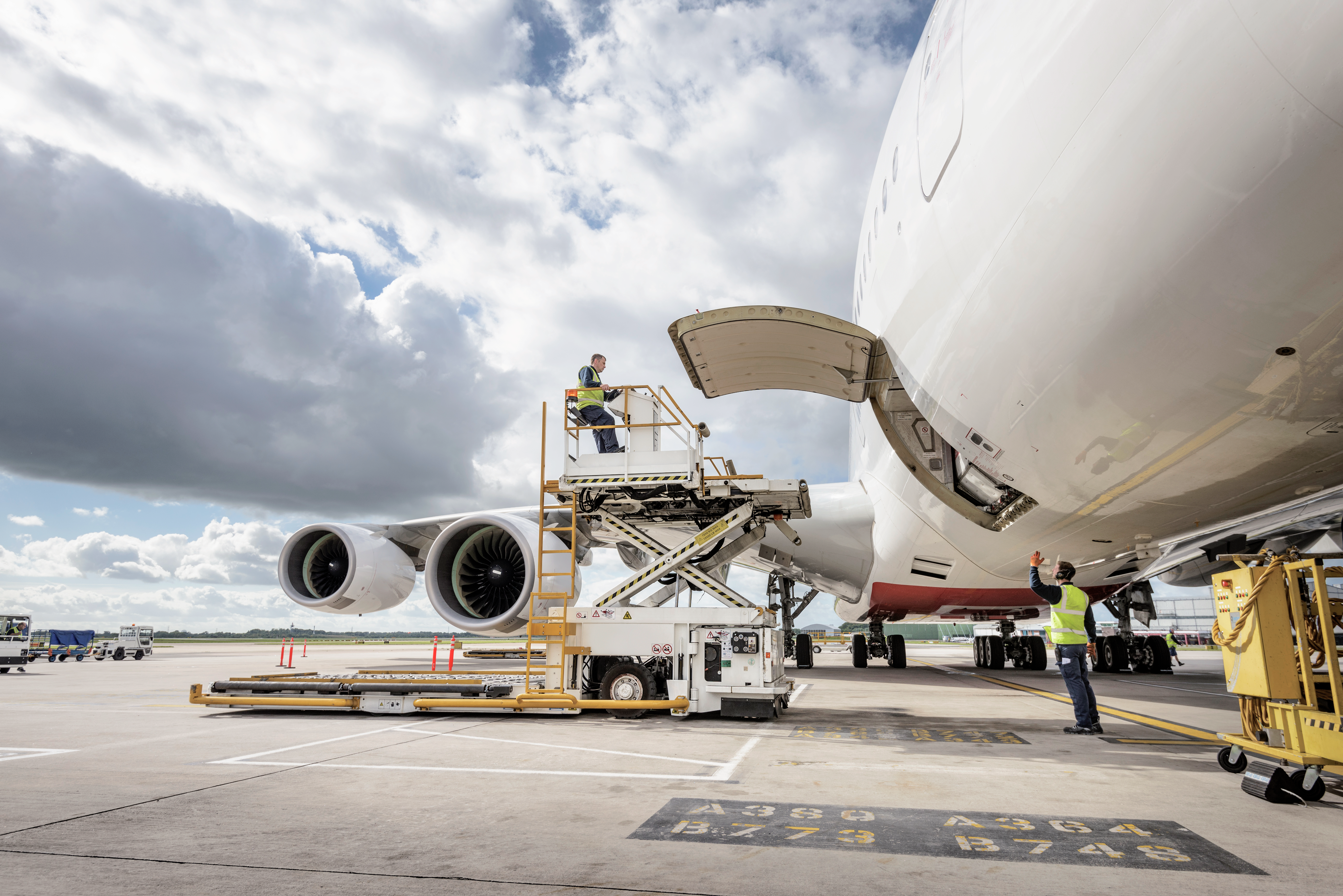 Airport ground crew load cargo into a large commercial aircraft at the terminal.