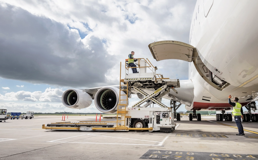 Airport ground crew load cargo into a large commercial aircraft at the terminal.