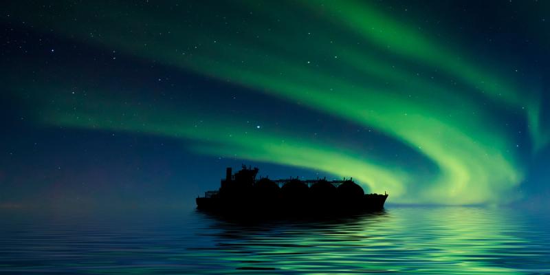 Silhouette of an LNG tanker at sea beneath green northern lights in a starry sky