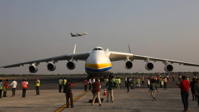 Giant Antonov cargo aircraft on a tarmac as a crowd of onlookers and ground crew gather around it