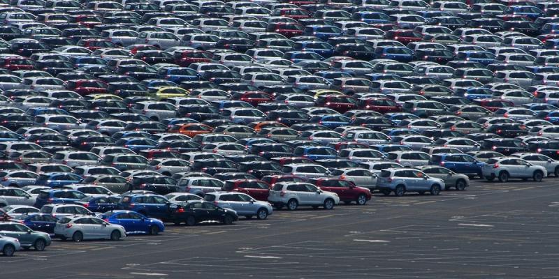 Vast parking lot filled with rows of new cars and SUVs awaiting distribution