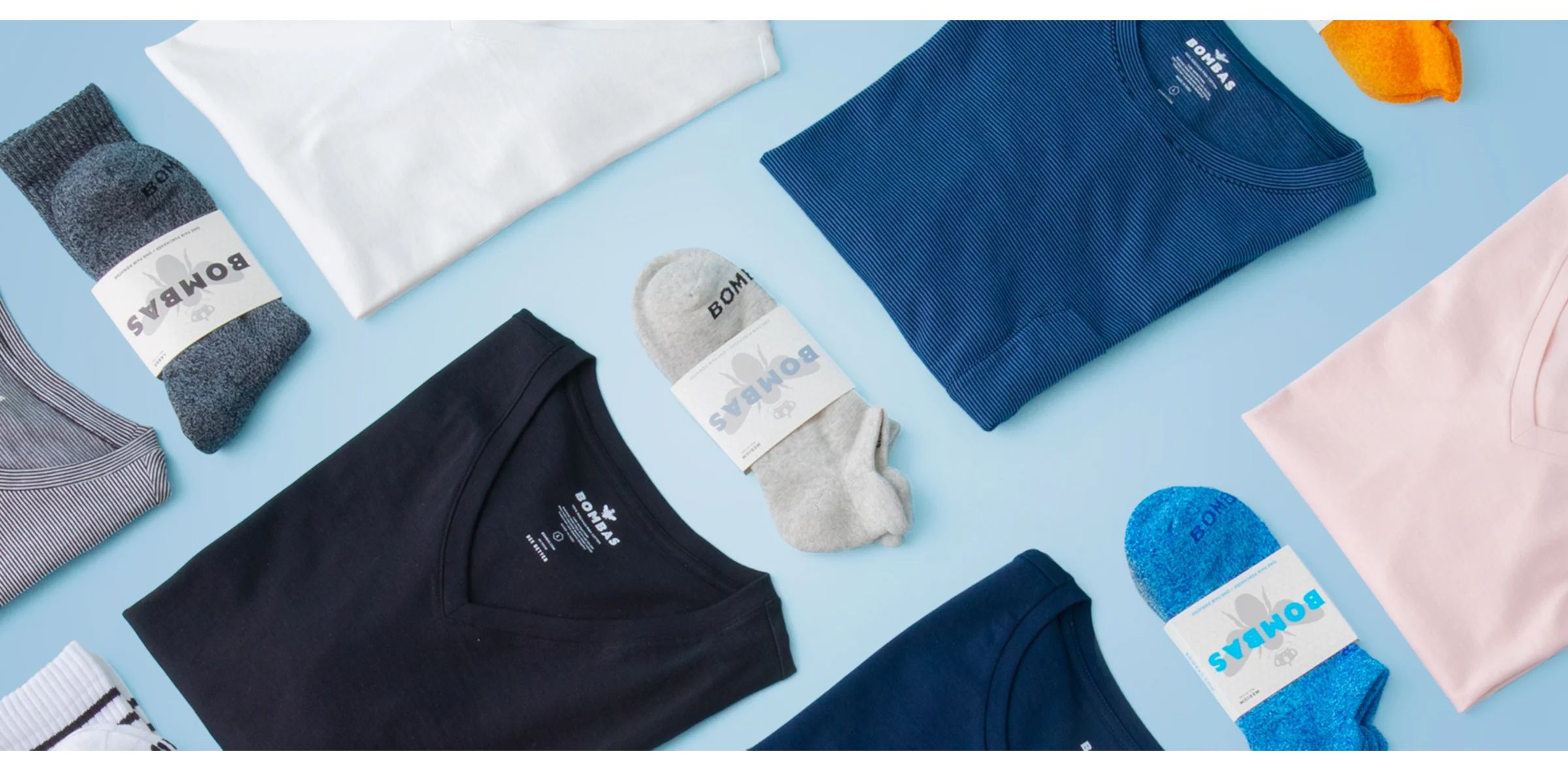 Folded clothing items and socks arranged in a flat lay display showcasing a clothing brand's apparel collection.