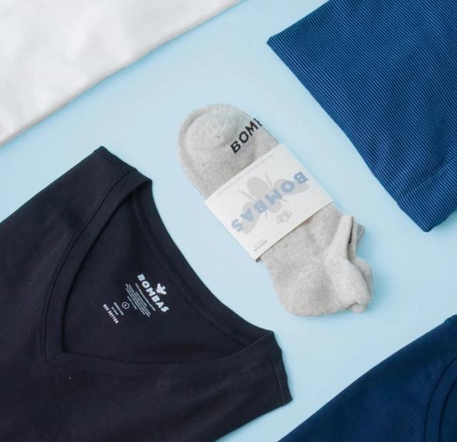 Folded clothing items and socks arranged in a flat lay display showcasing a clothing brand's apparel collection.