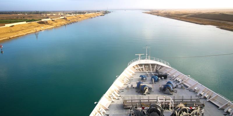 View from a ship's bow transiting the Suez Canal, with desert banks on both sides of the waterway