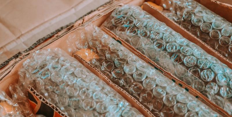 Close-up of cardboard boxes filled with glassware wrapped in bubble wrap for shipping