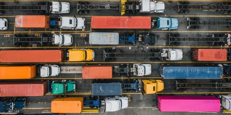 Aerial view of colorful shipping containers and trucks lined up in rows at a terminal