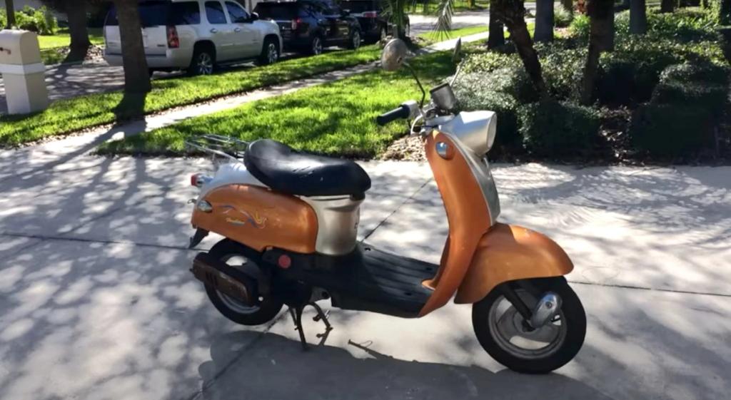 A motor scooter parked on a driveway.