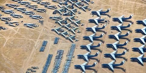 Aerial view of an aircraft boneyard with rows of parked decommissioned jets in the desert
