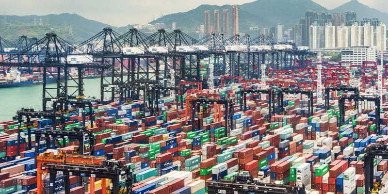 Aerial view of a dense container port packed with colorful stacked containers and a city backdrop.