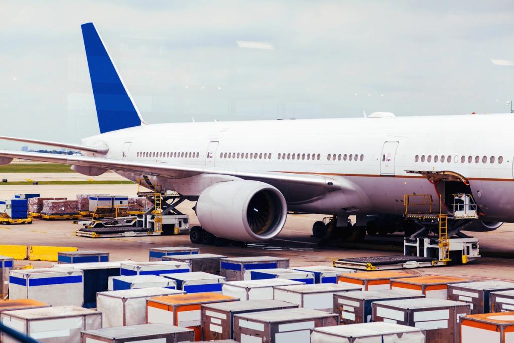 Wide-body cargo aircraft parked on an apron with air freight containers and ULDs staged in the foreground