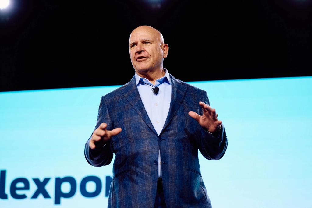 Bald man in a blue blazer gesturing while speaking on stage at a Flexport event