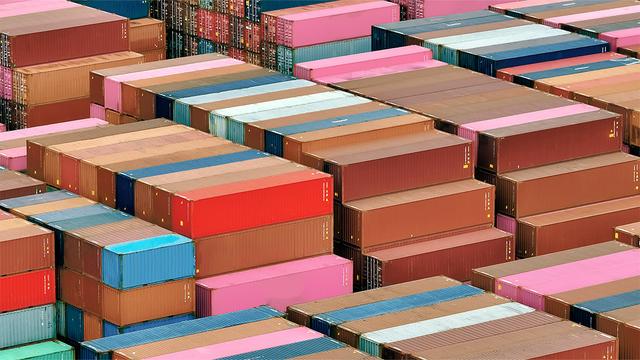Aerial view of rows of stacked multicolored shipping containers at a port terminal