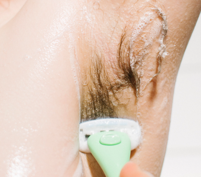 Close-up of a green Estrid razor shaving a lathered underarm