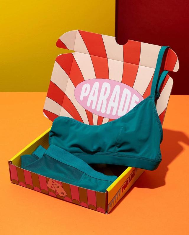 Teal Parade bralette and underwear in a colorful striped retro mailer box on an orange surface