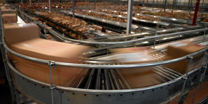 Motion-blurred cardboard parcels speed along curved conveyor belts in a fulfillment warehouse