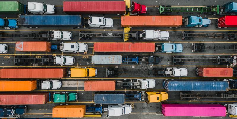 Aerial view of rows of cargo trucks and colorful shipping containers at a terminal