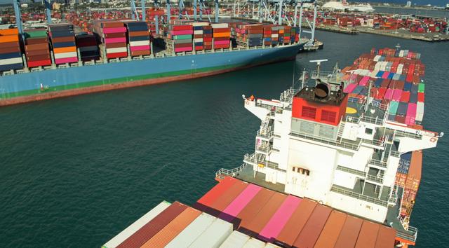 Aerial view of two container ships stacked with colorful shipping containers at a port terminal