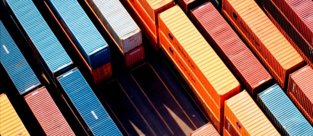 Aerial view of blue, red and orange shipping containers stacked in rows at a terminal