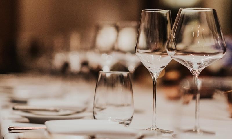 Empty wine and water glasses on a set restaurant table with a softly blurred warm background