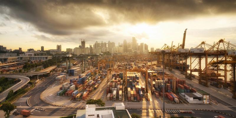 Aerial view of a sprawling container port and city skyline at golden sunset