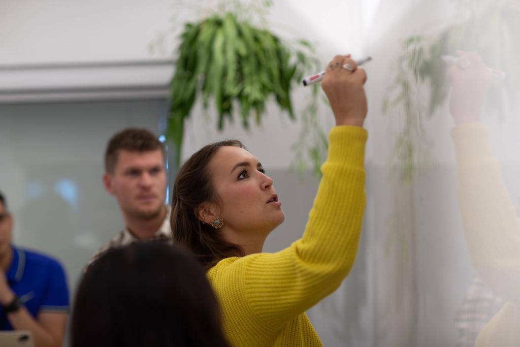 A Flexport colleague writing on a whiteboard while teammates look on during a meeting