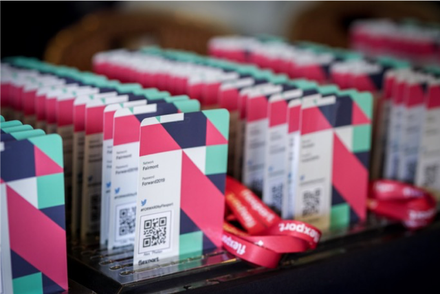 Rows of geometric-patterned event badges with QR codes and a red lanyard on a table